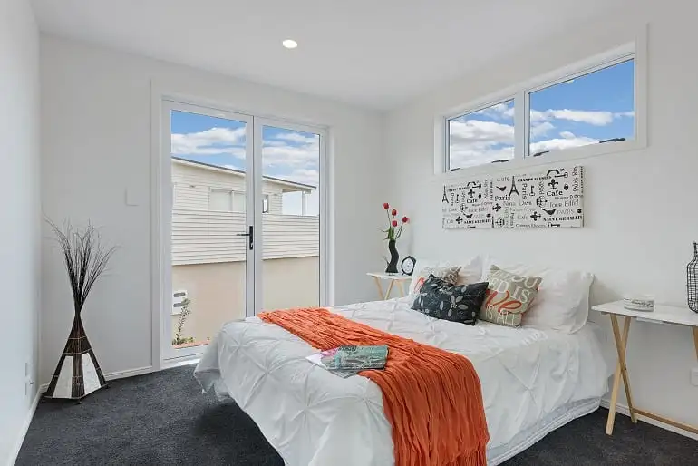 A bedroom with glass doors and a high window.