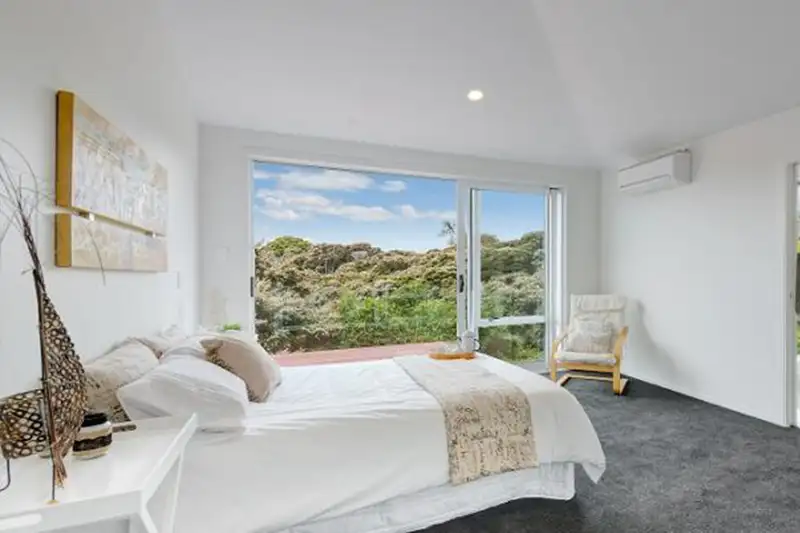 A bedroom with doors onto the deck and a view over the bush.