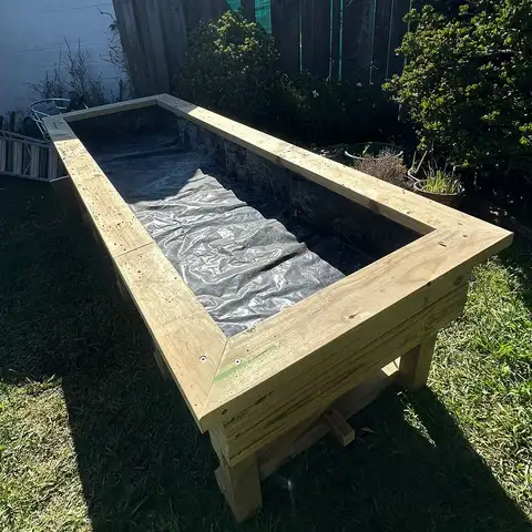 The raised bed lined with black plastic.