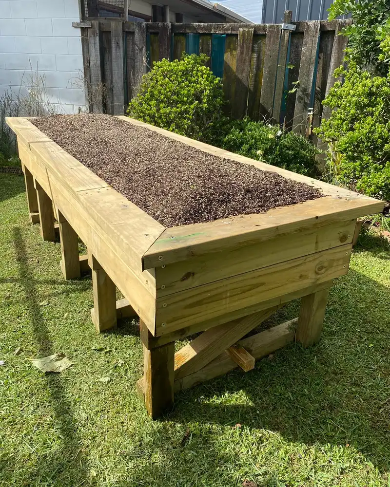 The finished raised garden bed, filled with soil, on sturdy timber legs.