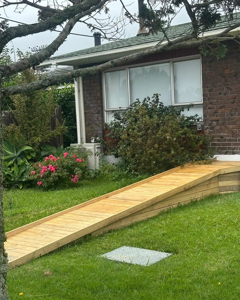 The timber ramp seen from the lawn, a long low slope rising to a level landing at the house.
