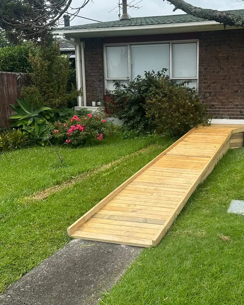 The finished timber wheelchair ramp, running from the front path across the lawn up to the brick house.